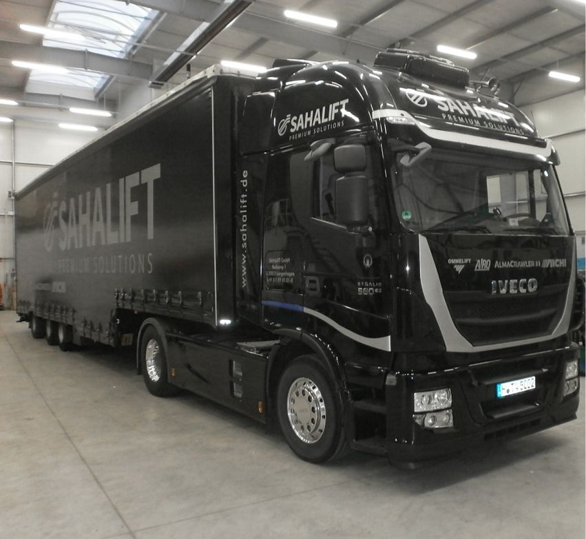 Ein schwarzer Iveco-Lkw mit dem Schriftzug "Sahalift Premium Solutions", der in einem Innenraum geparkt ist und sein elegantes Design und das Firmenlogo zur Geltung bringt.