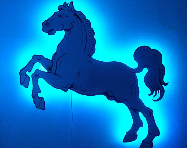 Eine stilisierte Silhouette eines sich aufbäumenden Pferdes, beleuchtet von einem leuchtenden blauen Licht vor einem dunklen Hintergrund.