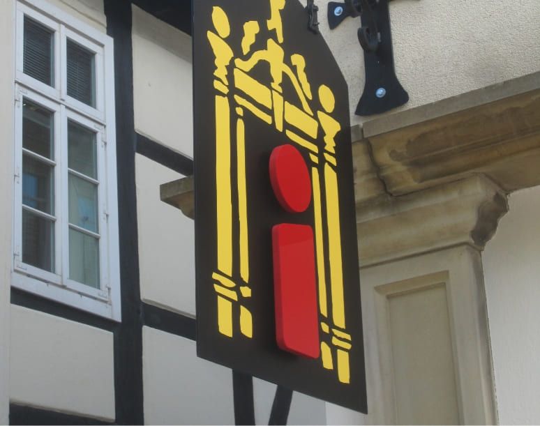 Ein buntes Schild mit einem gelben Wahrzeichen, das auf ein Informationszentrum hinweist.